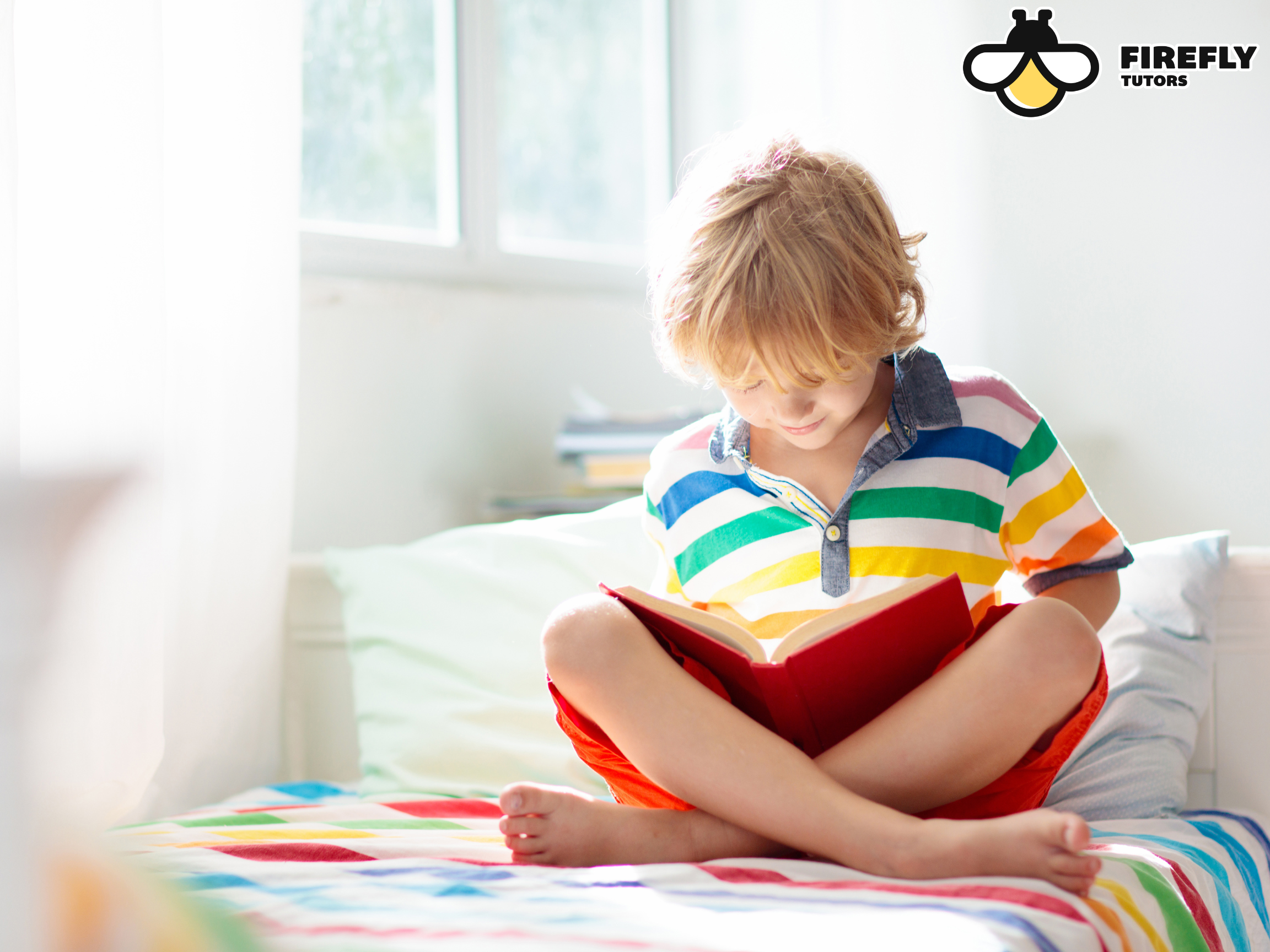 Young boy sitting cross-legged reading a book in a bright, sunlit room